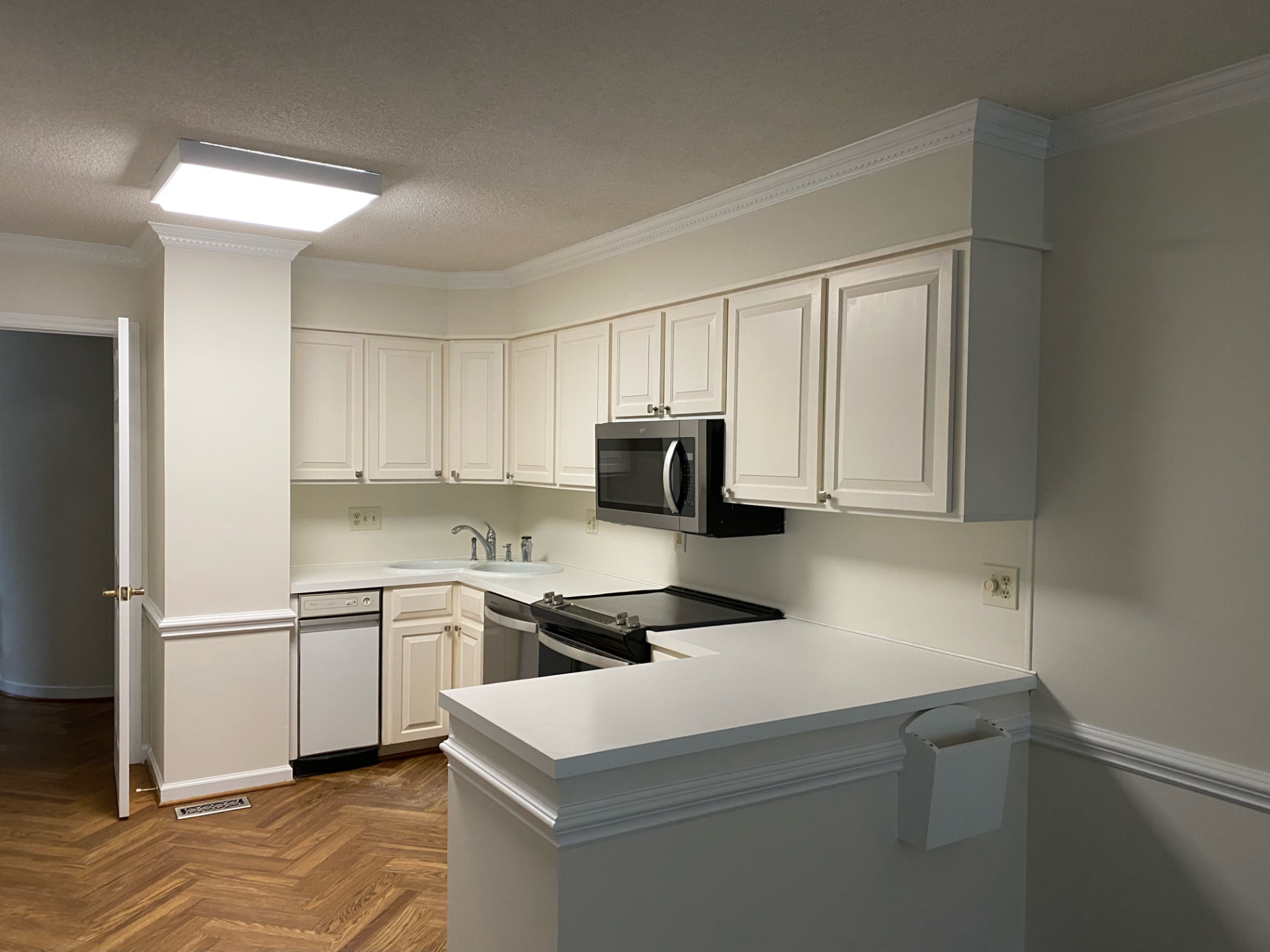 Refinished white kitchen cabinets with painted walls and crown molding
